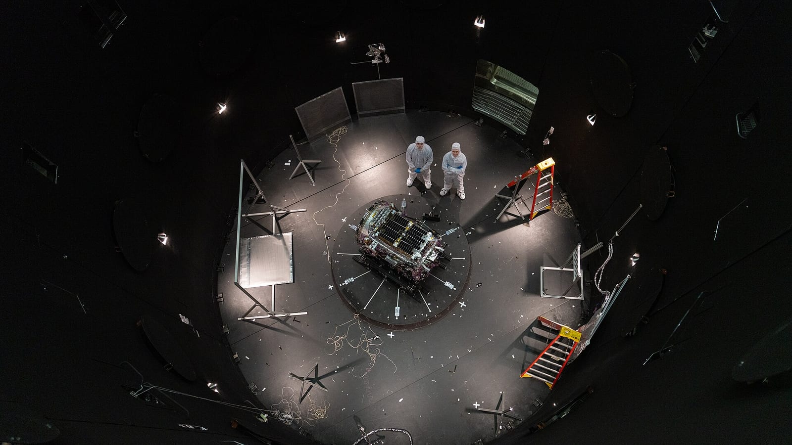 Kieran Wilson, LINK’s principal investigator, and Hunter Robertson, a space systems engineer, both at Katalyst Space, stand next to their spacecraft inside the SES (Space Environment Simulator) at NASA’s Goddard Space Flight Center in Greenbelt, Maryland, on April 17, 2026, ahead of thermal vacuum t